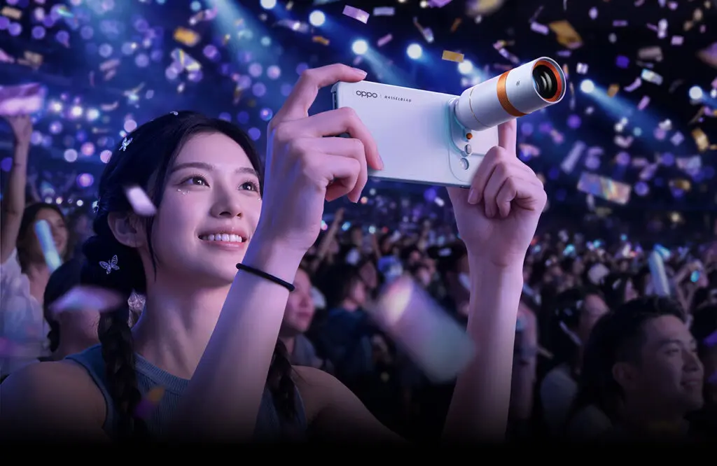 Cô gái cầm điện thoại OPPO Find X10 màu trắng gắn ống kính camera rời trong đại nhạc hội sôi động