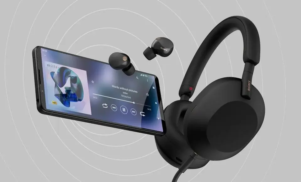 Điện thoại Sony Xperia 1 Mark VI màu đen hiển thị giao diện phát nhạc bên cạnh tai nghe chụp tai và tai nghe nhét tai